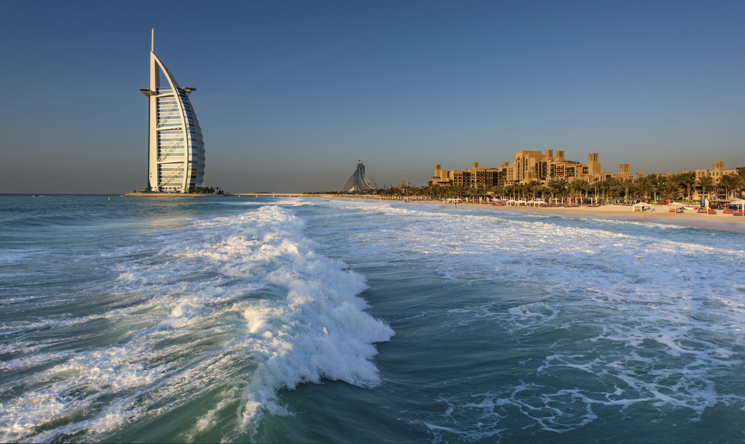 Cityscape of Dubai, United Arab Emirates, with the Burj Al Arab skyscraper on the coastline of the Persian Gulf in the distance.